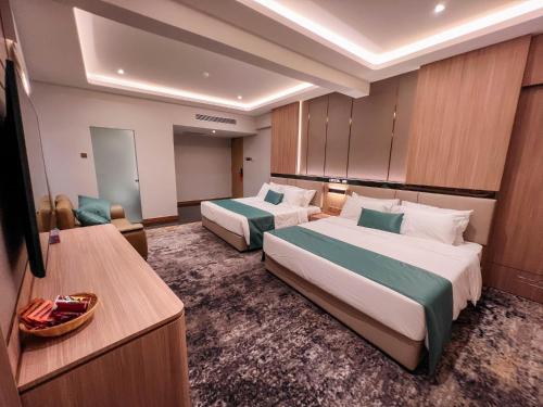 a hotel room with two beds and a television at Crystal Inn in Batu Pahat