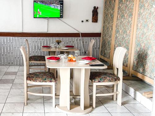 a white table with chairs and a tv on a wall at Hill View Hotel McCarthy Hills in Bortianor