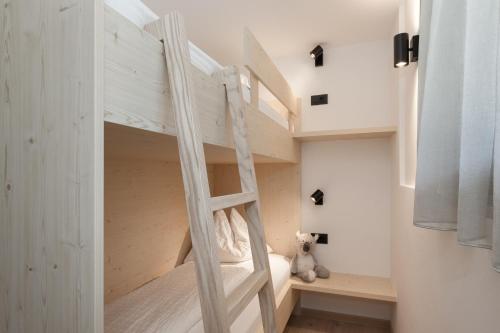 a bunk bed in a room with a ladder at Aparthotel Familiaris - Family Apartments - Pools & Spa in Dolomites in Valdaora