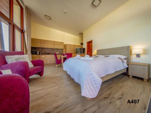 a bedroom with a large bed and two chairs at Apartmány Tatry in Vysoke Tatry - Stary Smokovec