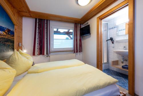 a small bedroom with two beds and a sink at Energiepension Schwaiger in Leogang
