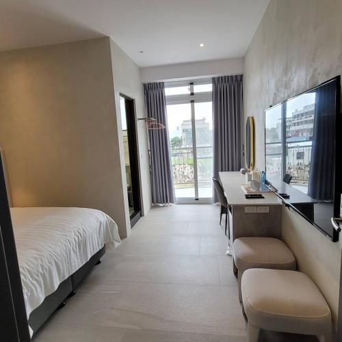 a hotel room with a bed and a desk and a television at 芙蘿拉萃旅 in Taitung City