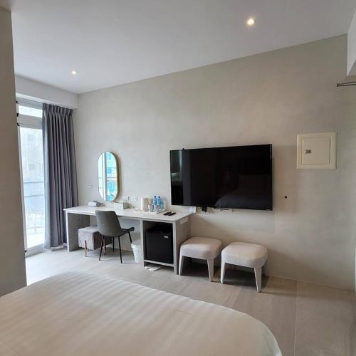 a bedroom with a desk and a tv on the wall at 芙蘿拉萃旅 in Taitung City
