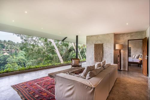 a living room with a couch and a large window at Hidden Gem Suites Ubud in Ubud