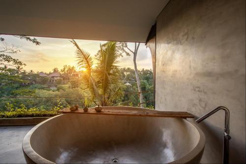 una vasca da bagno in una stanza con una grande finestra di Hidden Gem Suites Ubud ad Ubud