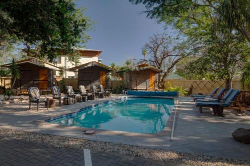 a swimming pool with lounge chairs and a house at Naankuse Travellers Inn in Windhoek
