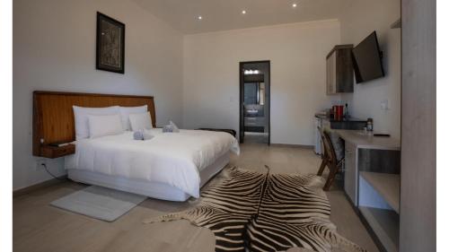 a bedroom with a white bed and a zebra rug at Sandune Game Lodge in Gobabis