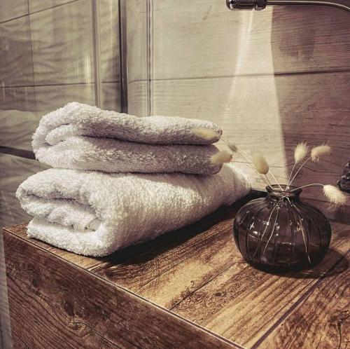 una pila de toallas en una mesa de madera con un jarrón en Areal Relax-Hotel en Senʼkovka
