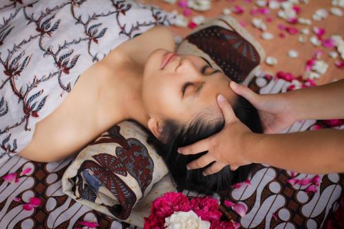 a woman laying on a bed with her eyes closed at Villa Borobudur Resort in Borobudur