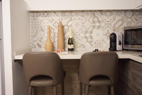 Catanese Proverb's House - Via Napoli في كاتانيا: مطبخ مع كونتر مع كرسيين وطاولة مع زجاجات النبيذ