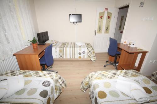 a room with two beds and a desk and a table at Sari Pension in Edirne