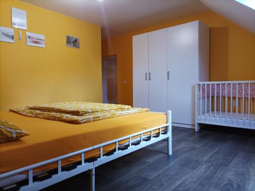 a bedroom with a crib and a yellow wall at MotoHostel Wolter - apartmán Leme in Všeň