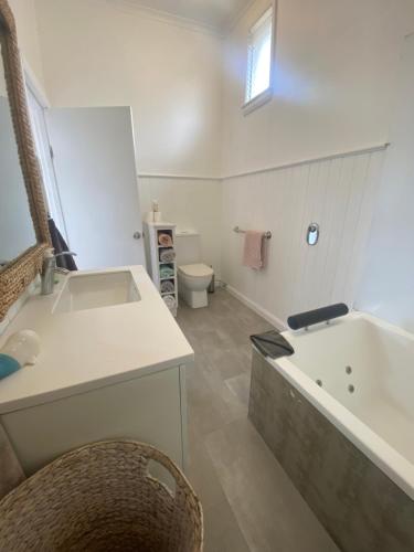 a bathroom with a sink and a tub and a toilet at The Ultimate Beach House in Kingston Beach