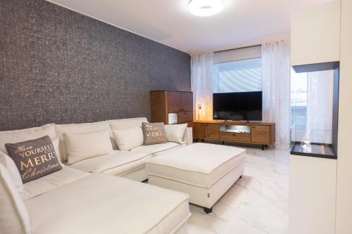 a living room with a white couch and a tv at City Garden Apartments 2 in Rovaniemi