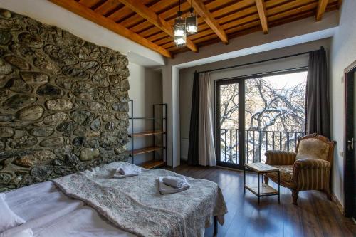 Mestia Hotel Amirani في ميستيا: غرفة نوم بحائط حجري وسرير وكرسي
