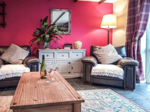 a living room with two couches and a table with wine glasses at Panteg Cottage in Cross Inn