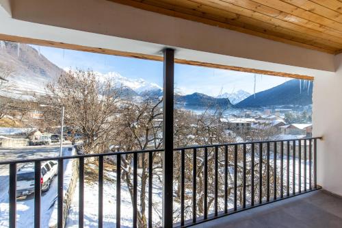 um quarto com uma varanda com vista para as montanhas cobertas de neve em Mestia Hotel Amirani em Mestia