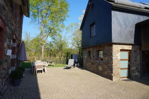 ein Backsteingebäude mit einer Terrasse mit Tischen und Stühlen in der Unterkunft Le Walkoti - cosy cottage with 2 bedrooms in Weismes