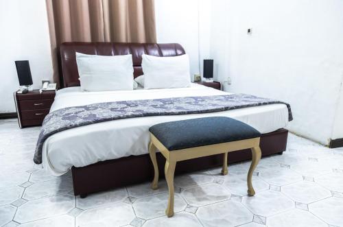 a bedroom with a large bed with a bench next to it at Hill View Hotel West Airport in Accra