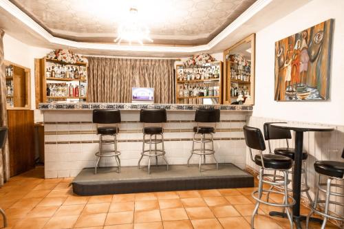 a bar in a restaurant with stools at Hill View Hotel West Airport in Accra