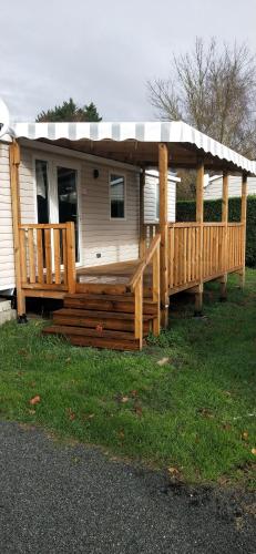 a mobile home with a porch and a deck at Camping Siblu les Charmettes in Les Mathes