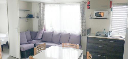 a living room with a purple couch and a kitchen at Camping Siblu les Charmettes in Les Mathes