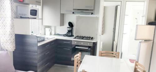 a small kitchen with a stove and a table at Camping Siblu les Charmettes in Les Mathes