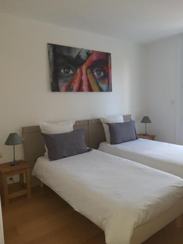 duas camas num quarto com um quadro na parede em La Grange em Cazouls-d Herault