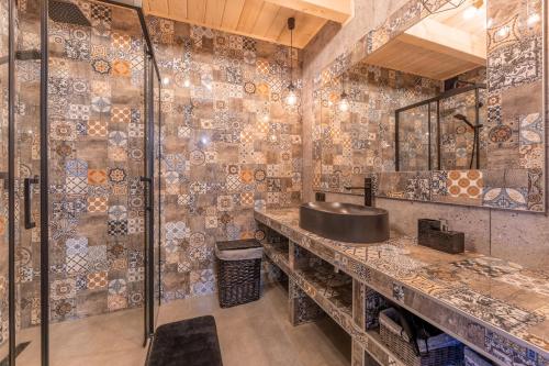 baño con lavabo y pared de mosaico en Chaty Skwirutowe Wzgórze - Domki Całoroczne, en Solina