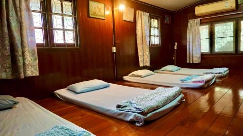 3 camas en una habitación con suelo y ventanas de madera en Tanachporn Homestay ธนัชพร โฮมสเตย์ เมืองจันทบุรี en Chanthaburi