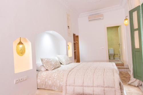 a white bedroom with a bed and a green door at Palais Riad Hida in Oulad Berhil
