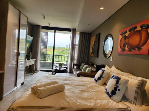 a bedroom with a large bed with a balcony at Zimbali Lakes Boulevard Suite 125 in Ballito