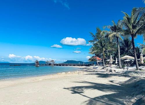 uma praia com palmeiras e o oceano em Gold Coast Phu Quoc Beach Resort em Phu Quoc