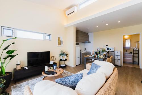 a living room with two white couches and a tv at Alpha Terrace Onna Hills in Onna