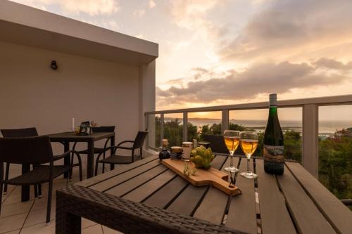 a wooden table with two glasses of wine on a balcony at Alpha Terrace Onna Hills in Onna