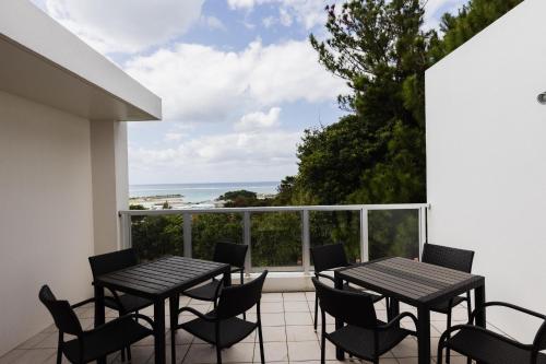 a balcony with tables and chairs and a view of the ocean at Alpha Terrace Onna Hills in Onna