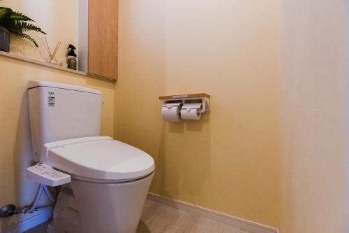a bathroom with a toilet and two rolls of toilet paper at Alpha Terrace Onna Hills in Onna
