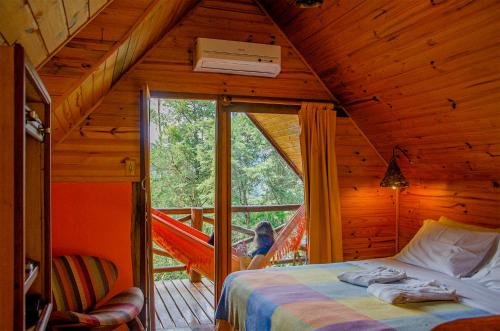 a bedroom with a hammock in a log cabin at Pousada Rancho Das Framboesas in Visconde De Maua