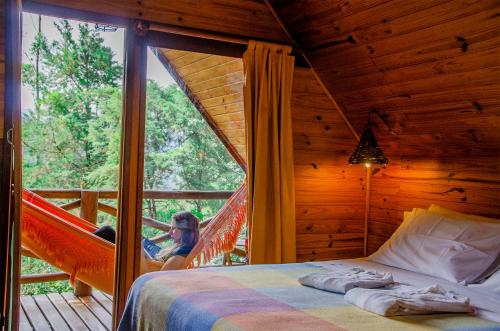 a girl is sitting on a hammock in a tree house at Pousada Rancho Das Framboesas in Visconde De Maua