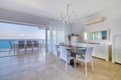 a dining room with a table and chairs and the ocean at Stunning Seafront Lux Apt Fort Cambridge wt POOL in Sliema
