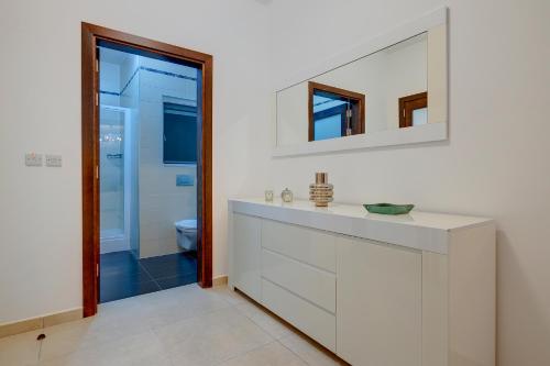 a bathroom with a sink and a mirror at Stunning Seafront Lux Apt Fort Cambridge wt POOL in Sliema