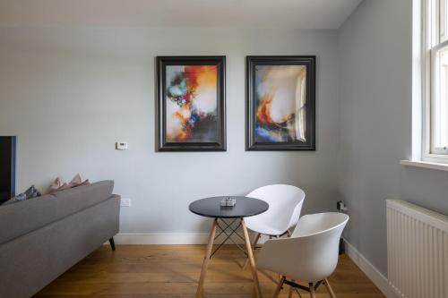 a living room with a table and three pictures on the wall at Luxurious Private One Bedroom Apartment in Braintree with Free Parking Near City Centre in Braintree