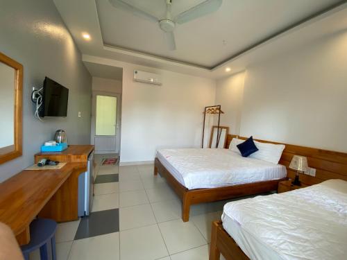 a hotel room with two beds and a desk at MAY Bungalow in Mui Ne