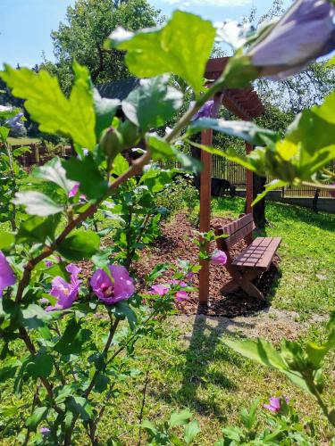 a park bench in a garden with purple flowers at Chata pod Mogielicą komfortowe pokoje z widokiem na Mogielicę 1000m od tras wokół góry Mogielica in Słopnice