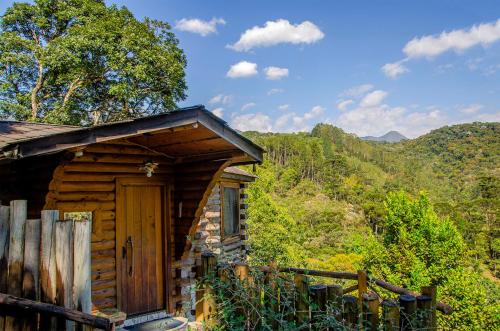 a cabin with a wooden door in the mountains at Pousada Rancho Das Framboesas in Visconde De Maua