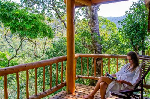 a woman sitting on a porch reading a book at Pousada Rancho Das Framboesas in Visconde De Maua