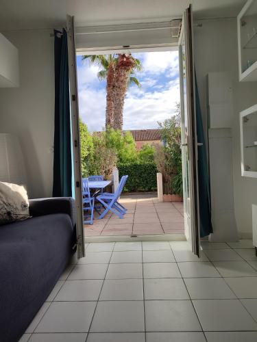Une porte ouverte s'ouvre sur une terrasse avec un palmier. dans l'établissement Villa Club T2 à Mar Vivo, plages à pieds, piscine, à La Seyne-sur-Mer