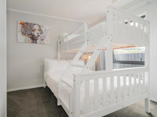 een witte slaapkamer met een stapelbed en een ladder bij Chill-out Beach Bach - Whangamata Holiday Home in Whangamata