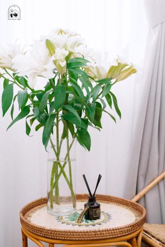 a glass vase with white flowers on a table at Chi's Homestay & Coffee in Hue