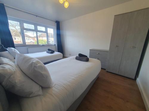 sypialnia z 2 łóżkami i oknem w obiekcie Luxury 5 - Spacious Contractor's Delight with 4 Bedrooms and Ample Driveway Parking w Luton